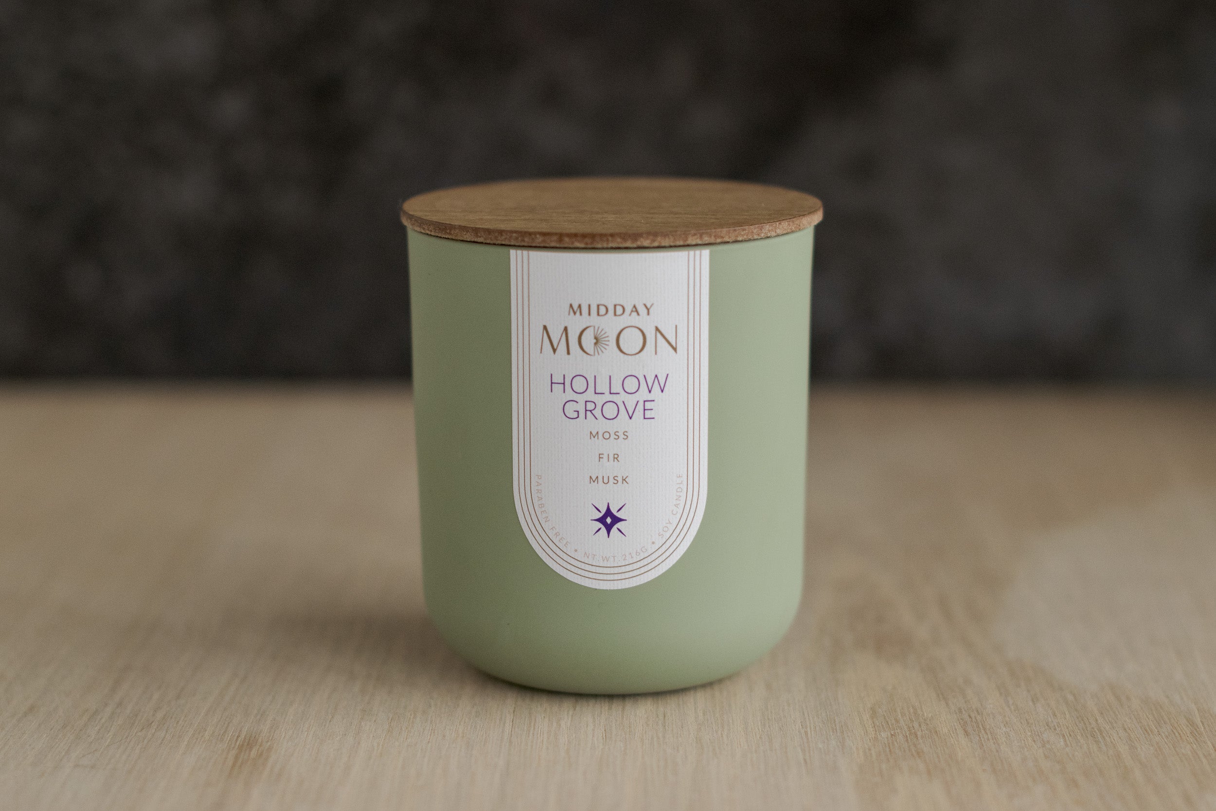 A scented candle in a green jar with a wooden lid.