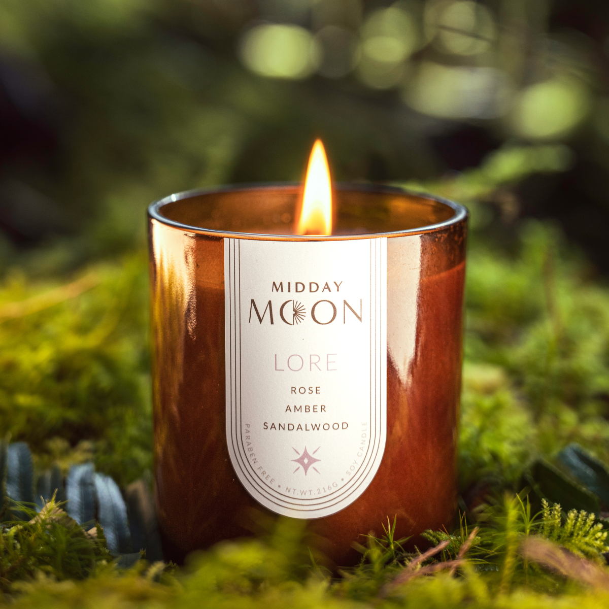 Lore scented candle on a lush forest backdrop. Rose, amber, and sandalwood scented candle.