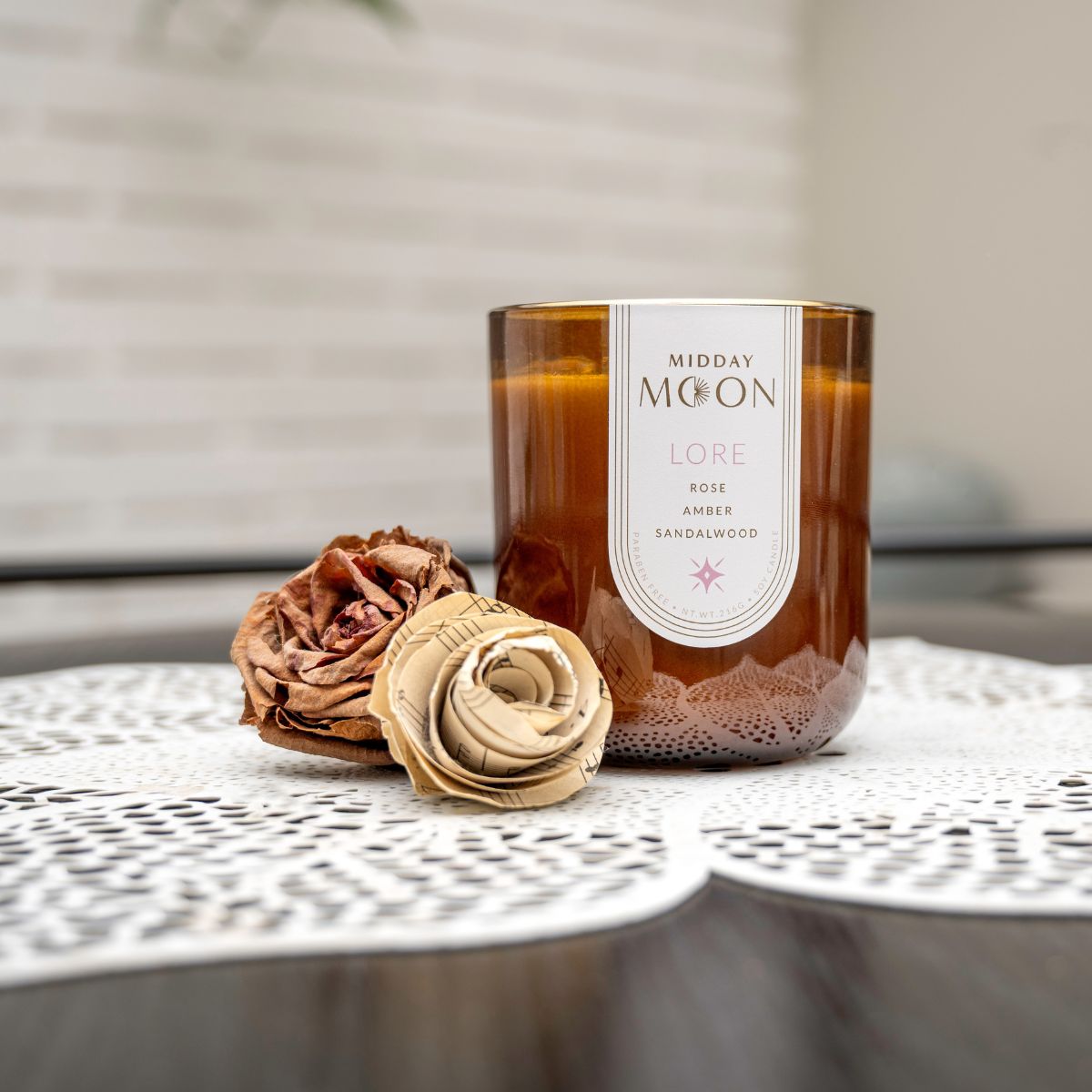 Rose scented candle staged with paper roses on a silk doily. Mid day moon soy candle.
