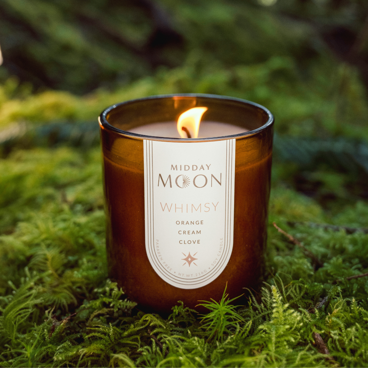 Whimsy scented candle on a lush forest backdrop. Orange creamsicle scented candle.
