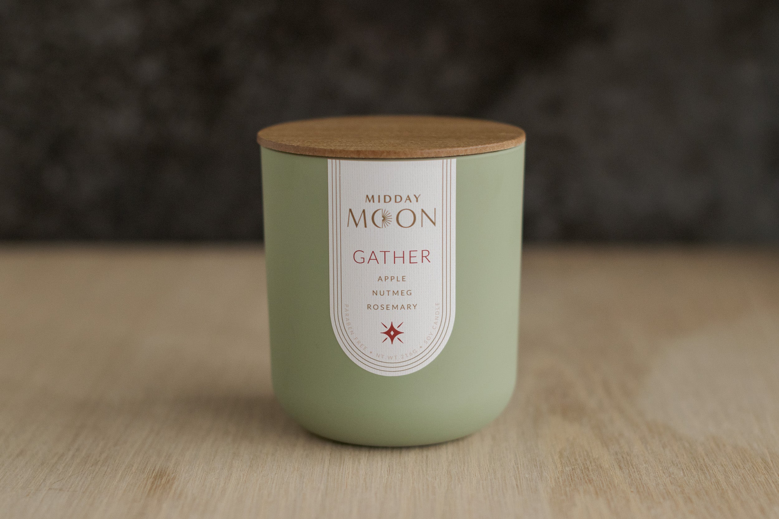 Gather candle in a green jar with a wooden lid on a wooden surface