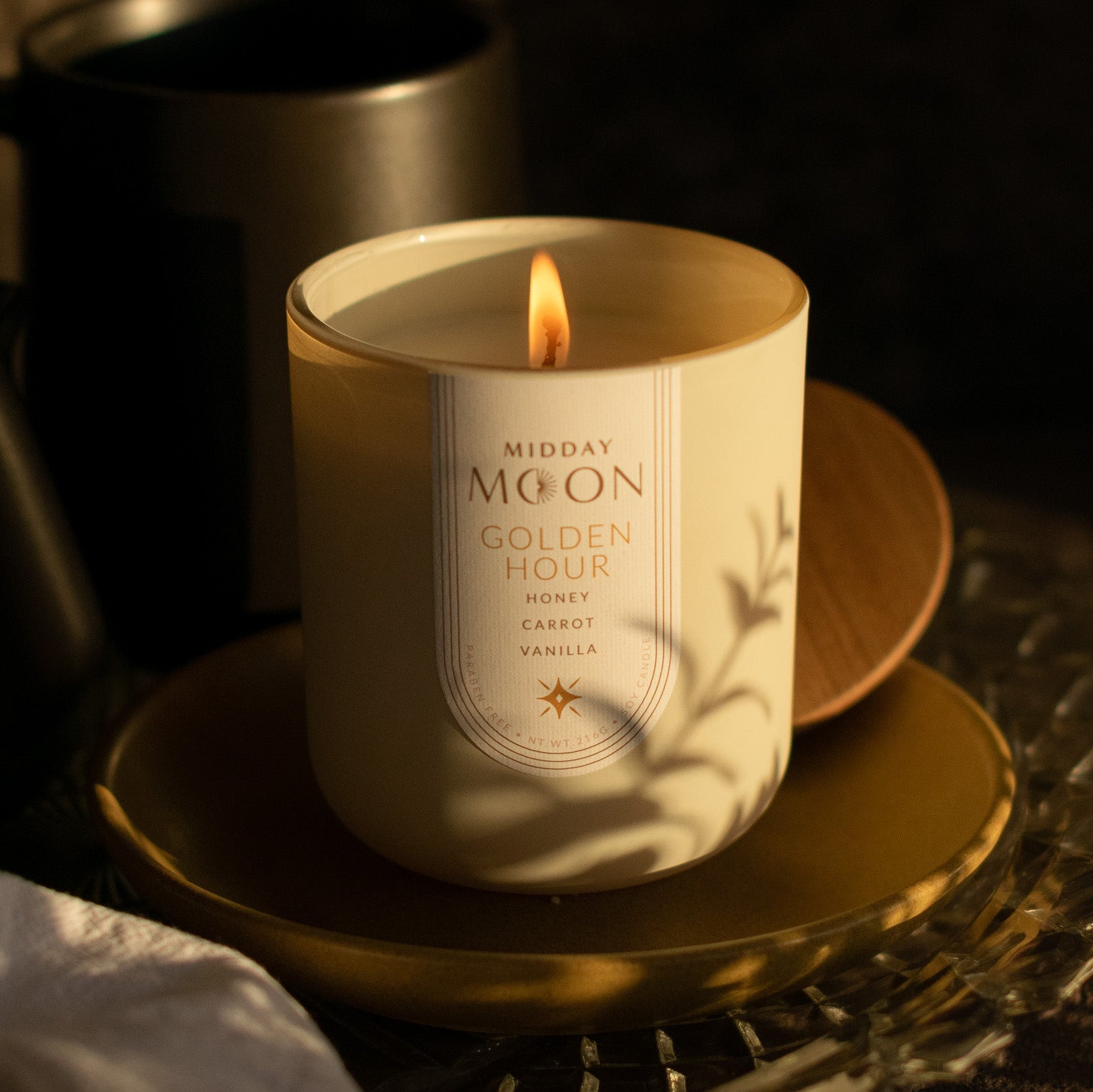 Midday Moon's Golden Hour candle bathed in the soft light of golden hour. There is a shadow of a plant cast across the jar.