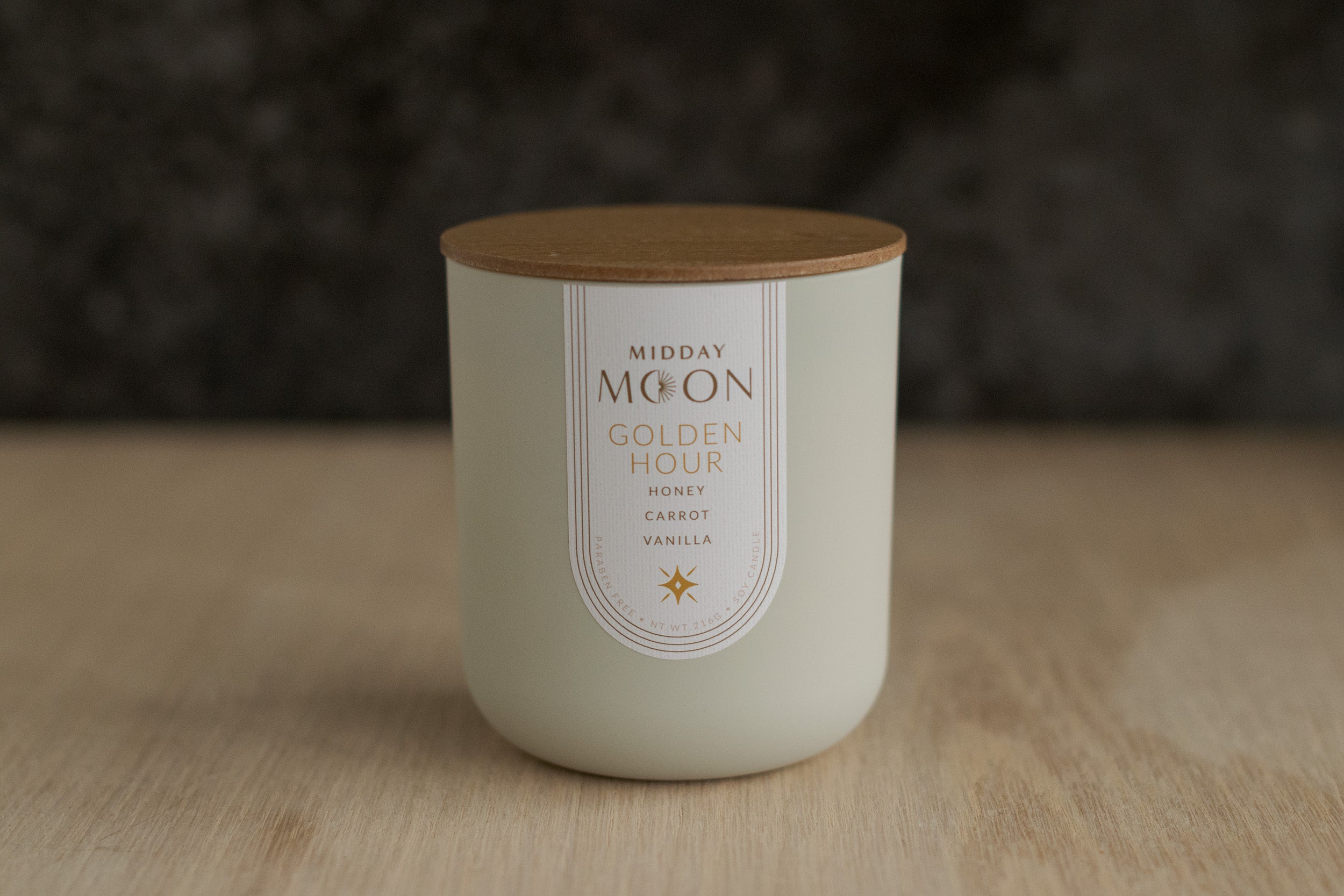 Midday Moon's Golden Hour candle displayed on a plain wooden surface.