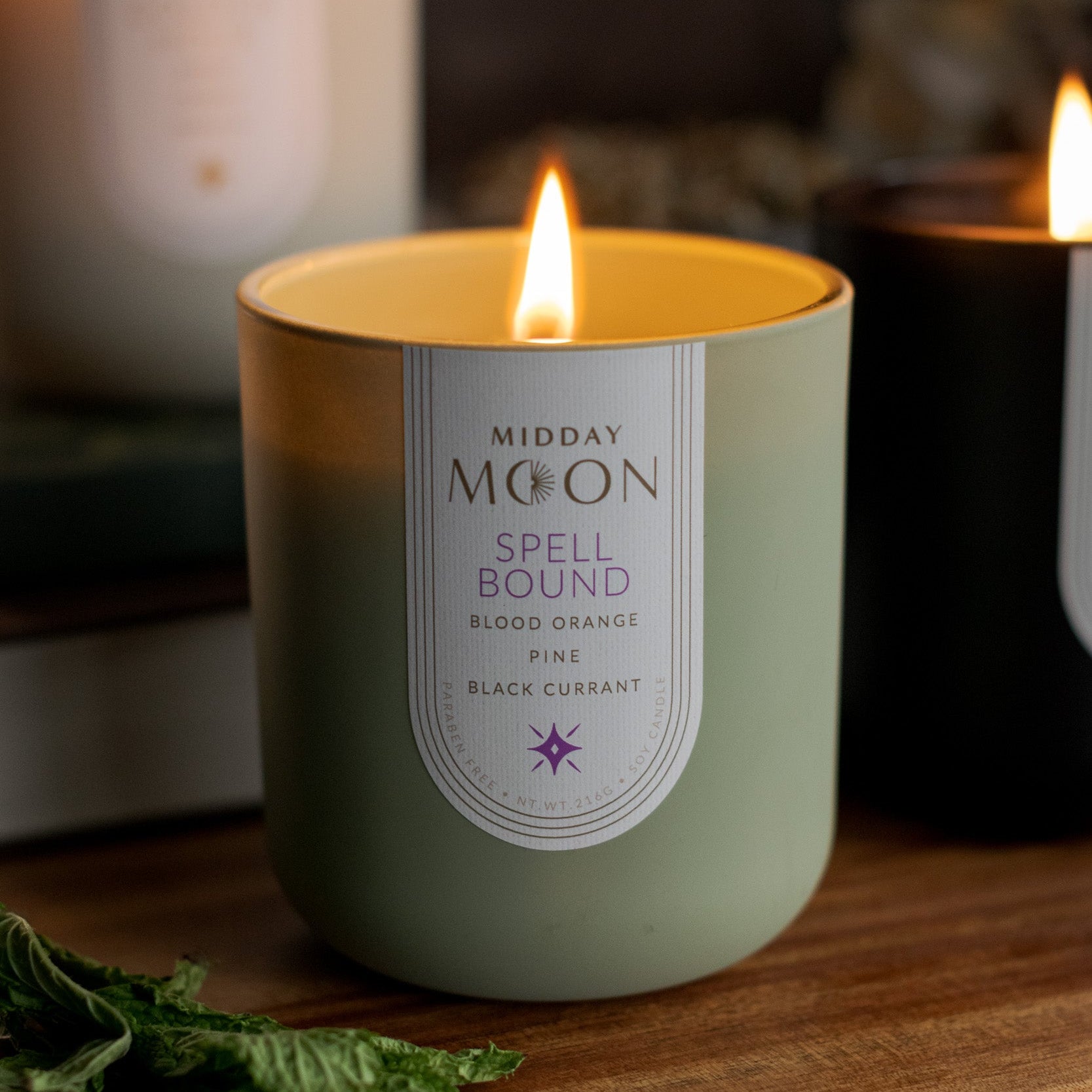 Midday Moon spellbound candle with other candles lit in the background.